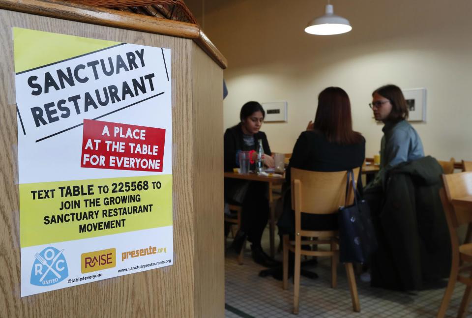 In this Wednesday, Jan. 18, 2017 photo, a sanctuary restaurant sign is shown inside Russell Street Deli in Detroit. Dozens of restaurants are seeking “sanctuary” status, a designation owners hope will help protect employees in an immigrant-heavy industry and tone down fiery rhetoric sparked by the presidential campaign. (AP Photo/Paul Sancya)