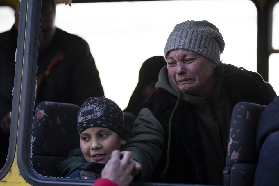 Mykolaivna Shankarukina, 54, leaving from the Ukrainian Red Cross, reacts while she says goodbye to her son as her grandson looks on, in Mykolaiv, southern Ukraine, on Monday, March 28, 2022. Shankarukina and her family evacuated from Sablagodante village at Mykolaiv district that have been attacked by the Russian army. She and her grandson go to Odesa and from there to Prague, as the rest of the family (son, daughter in law and little grandson) will stay in Mykolaiv in a center for displaced residents. (AP Photo/Petros Giannakouris)