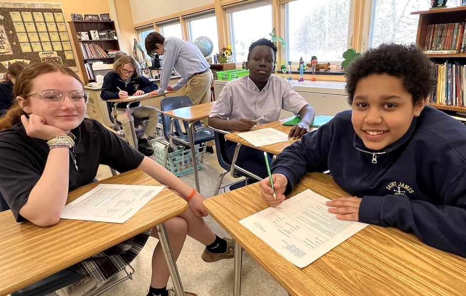 St. James School students, from left, Alaina Shultz, Kuat Rag and Del Coleman-Pierce work on a group exercise in their financial literacy elective on March 24.