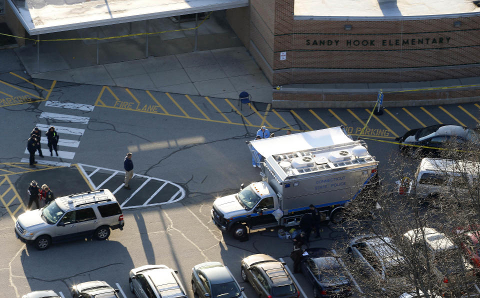 FILE - In this Dec. 14, 2012, file photo, officials stand outside of Sandy Hook Elementary School in Newtown, Conn., where authorities say gunman Adam Lanza opened fire inside school killing 20 first-graders and six educators at the school, and killed himself as police arrived. Documents from the investigation into the massacre at Sandy Hook Elementary School are shedding light on the Lanza's anger, scorn for other people, and deep social isolation in the years leading up to the shooting. (AP Photo/Julio Cortez, File)