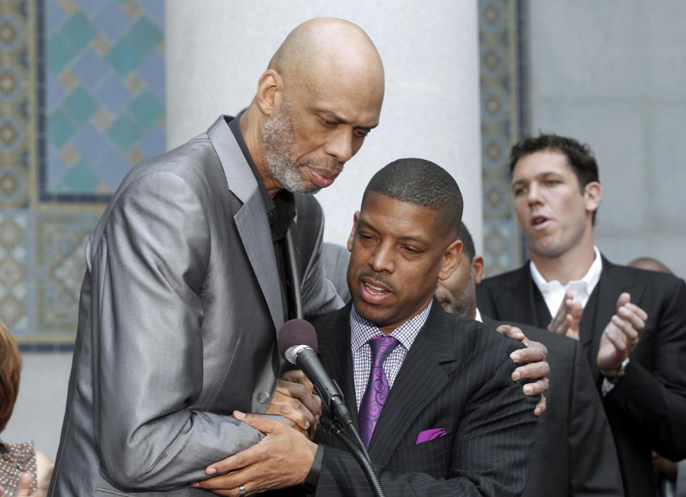 Sacramento, Calif., Mayor Kevin Johnson, center, and Hall of Famer Kareem Abdul-Jabbar embrace during a news conference outside City Hall in Los Angeles Tuesday, April 29, 2014, after Johnson's comments on the decision by NBA commissioner Adam Silver to ban Los Angeles Clippers owner Donald Sterling from basketball for life in response to racist comments the league says Sterling made in a recorded conversation. Former NBA player Luke Walton applauds at rear right rear. (AP Photo)