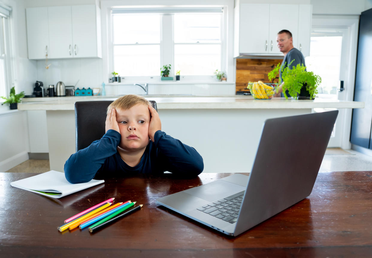 School boy watching online education classes feeling bored and depressed at home. COVID-19 pandemic forces children and teachers online learning.