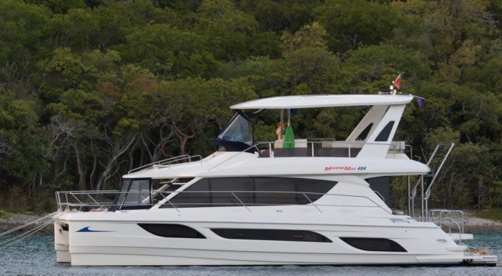 Side view of a MarineMax (HZO) boat on the water with trees in background