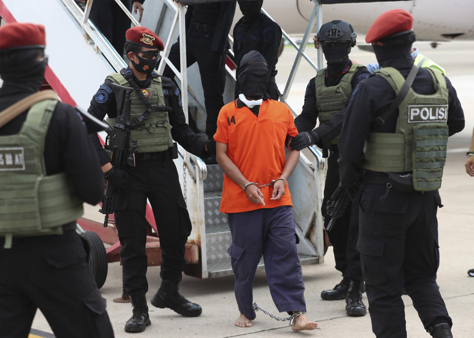 Police officers escort suspected militant Upik Lawanga, center, upon arrival at Soekarno-Hatta International Airport in Tangerang, Indonesia, Wednesday, Dec. 16, 2020. Indonesian authorities on Wednesday transferred 23 suspected militants arrested in recent weeks to the country’s capital. Among them are Aris Sumarsono, known as Zulkarnaen, and Lawanga, the ringleaders of the al-Qaida-linked Jemaah Islamiyah network who have eluded capture for more than a decade. (AP Photo/Achmad Ibrahim)