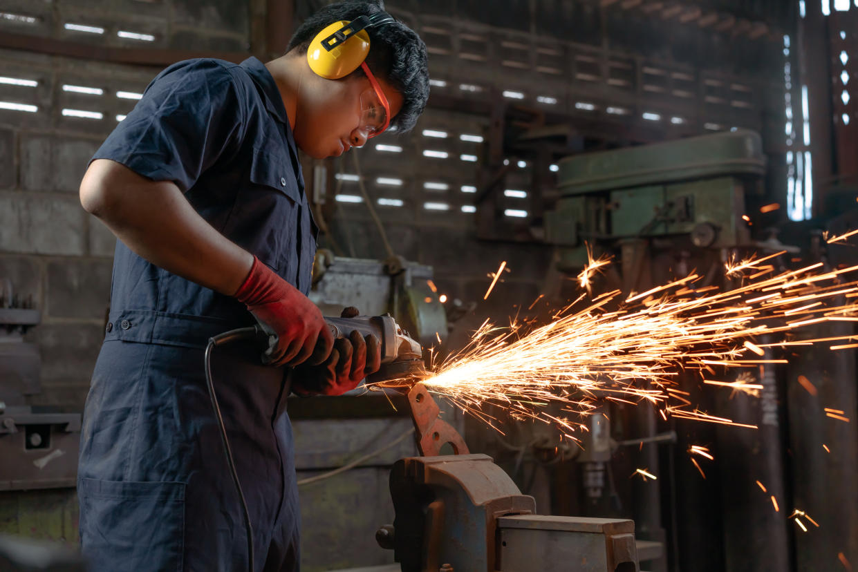 Engineer operating angle grinder hand tools in manufacturing factory. Photo: Getty