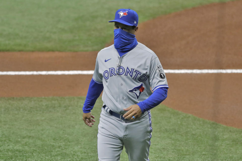Toronto Blue Jays manager Charlie Montoya wears a protective face mask as he walks back to the dugout after delivering the line up card before a baseball game against the Tampa Bay Rays Friday, July 24, 2020, in St. Petersburg, Fla. (AP Photo/Chris O'Meara)