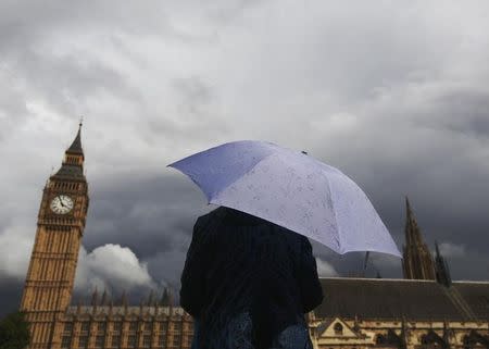 A woman looks towards dark clouds over the Houses of Parliament in central London August 11, 2014. REUTERS/Luke MacGregor