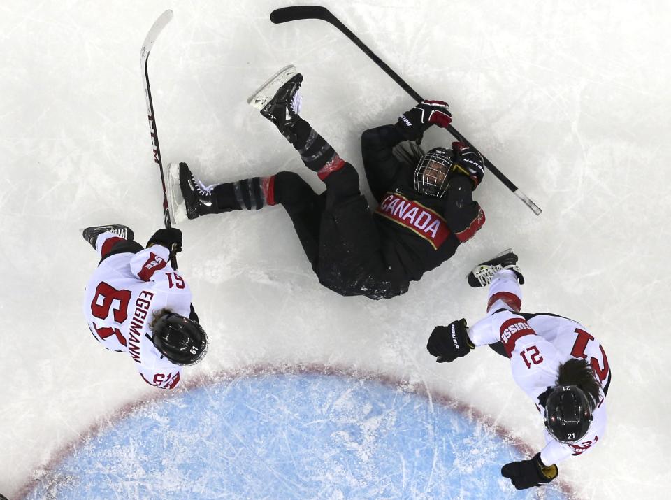 Canada's Natalie Spooner is knocked to the ice by Switzerland's Romy Eggimann (L) and Laura Benz during the second period of their women's ice hockey game at the Sochi 2014 Winter Olympics February 8, 2014. REUTERS/Mark Blinch (RUSSIA - Tags: SPORT ICE HOCKEY OLYMPICS TPX IMAGES OF THE DAY) ATTENTION EDITORS: PICTURE 15 OF 22 FOR PACKAGE 'SOCHI - EDITOR'S CHOICE' TO FIND ALL IMAGES SEARCH 'EDITOR'S CHOICE - 08 FEBRUARY 2014'