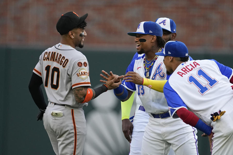 San Francisco Giants third baseman Johan Camargo (10), a former Atlanta Braves player, chats with Braves right fielder Ronald Acuña Jr. (13) before a baseball game Saturday, Aug. 19, 2023, in Atlanta. (AP Photo/John Bazemore)