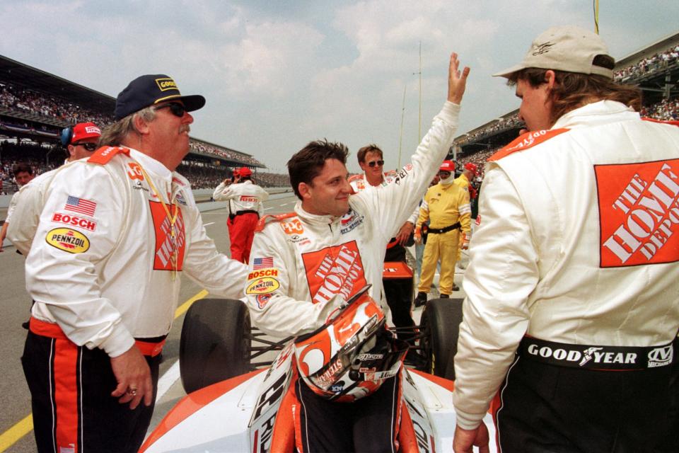 IRL driver Tony Stewart, center, waves to fans after finishing the Indy 500 May 30, 1999. His crew chief, Larry Curry, is at left.