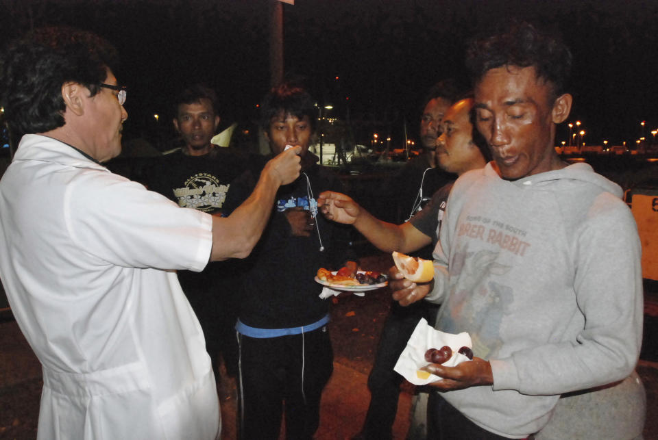 FILE - In this May 13, 2016, file photo, Dr. Craig Nakatsuka, left, distributes medication and fruit to undocumented foreign fishermen who work aboard American fishing boats in Honolulu. The doctor comes to Pier 38 with a church outreach project that holds services for the men twice a week. He said he sees problems ranging from high blood pressure to skin infections due to a lack of gloves or improper gear and is concerned about the possibility of scurvy from a lack of fruits and vegetables. On Friday, Sept. 18, 2020 the Hawaii Supreme Court heard arguments on the legality of issuing licenses to foreign workers in Hawaii's longline commercial fishing fleet, which for years has been under scrutiny after an Associated Press investigation revealed claims of human trafficking and questionable labor practices.(AP Photo/Caleb Jones, File)