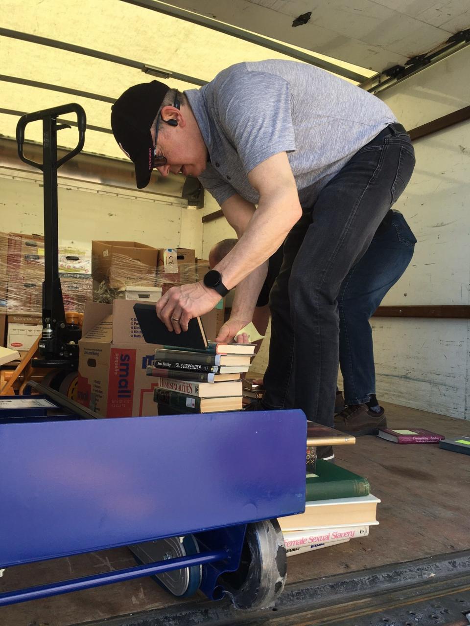 Robert Levy boxes some books that spilled from cartons in transit to Laurel Park Place in Livonia, where the annual Bookstock used book and media sale will be held April 23-30. He drove a rented truck to the mall Thursday with four pallets of books, slightly more than a thousand all told from the collection of his late father, Stanley. Craig Tomish, in the background, who works for Levy at Holo-Source Corp., was copilot and co-retriever of the spilled books. As a physician, the elder Levy's many areas of interest in books included human sexuality.