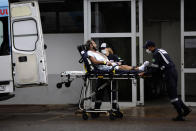 Healthcare workers receive a patient suspected of having COVID-19 at the public HRAN Hospital in Brasilia, Brazil, Monday, March 8, 2021. (AP Photo/Eraldo Peres)