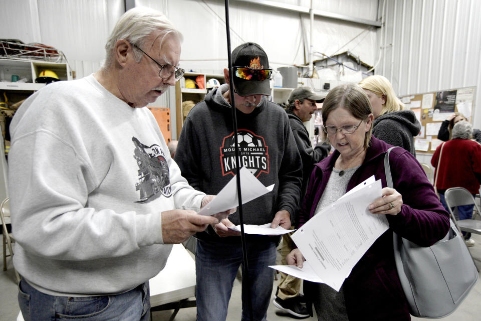 In this Oct. 24, 2019 photo, Richard Apking, left, and Debbie Johnson, right, examine documents following a town hall meeting at the fire hall in Winslow, Neb where relocating the village was discussed. It took only minutes for swift-moving floods from the Elkhorn River to ravage tiny Winslow this spring, leaving nearly all its 48 homes and businesses uninhabitable. Now, the couple dozen residents still determined to call the place home are facing a new challenge: Moving the entire town about three miles away to higher ground. (AP Photo/Nati Harnik)