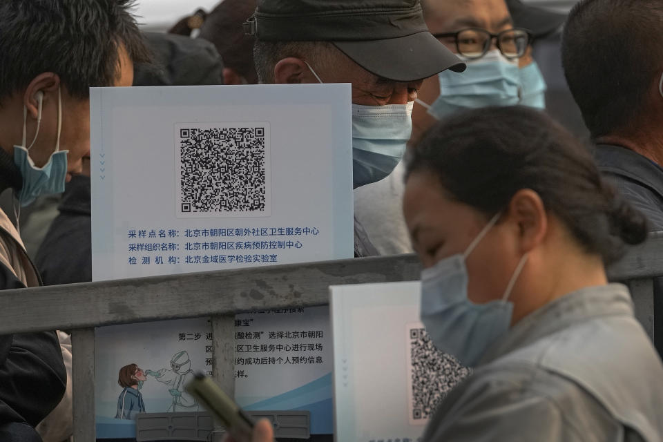 Service sector workers wearing face masks to help curb the spread of the coronavirus line up to receive a swab for the COVID-19 test during a mass testing in Beijing, Friday, Oct. 29, 2021, following a spike of the coronavirus in the capital and other provincials. (AP Photo/Andy Wong)