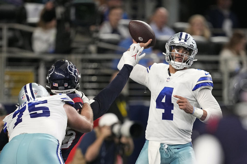 Dallas Cowboys quarterback Dak Prescott (4) throws an interception under pressure from Houston Texans linebacker Ogbonnia Okoronkwo (45) during the second half of an NFL football game, Sunday, Dec. 11, 2022, in Arlington, Texas. (AP Photo/Tony Gutierrez)