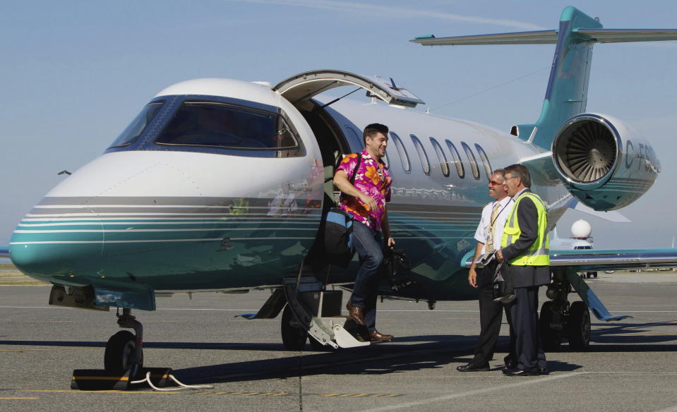 This Aug. 17, 2011 file photo, Jaeger Mah, left, is greeted by Vancouver International Airport CEO Larry Berg, right, and pilot Brent Fishlock as he steps off a Learjet upon arrival at the airport after a short tour in Richmond, B.C. The iconic Learjet, which carried generations of business executives and was made famous in pop songs, is about to fade into aviation history. Canada’s Bombardier said Thursday, Feb. 11, 2021 it will end production of the Learjet later this year. (Darryl Dyck/The Canadian Press via AP)