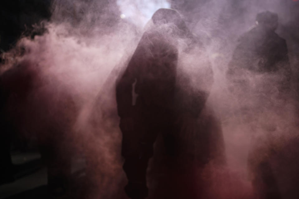 Demonstrators are silhouetted during a march against pension reforms in Lyon, central France, Tuesday, Feb. 7, 2023. Public transportation, schools and electricity, oil and gas supplies were disrupted on Tuesday in France as demonstrators are taking to the streets for a third round of nationwide strikes and protests against the government's pension reform plans. (AP Photo/Laurent Cipriani)