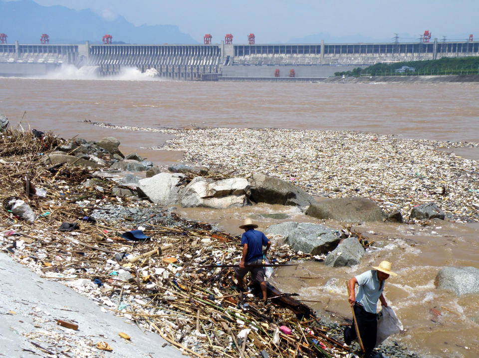 Two workers clean up trash along the bank of the Yangtze River near the Three Gorges Dam in Yichang, in central China's Hubei province on August 1, 2010. Layers of trash floating in the Yangtze river are threatening to jam China's massive Three Gorges hydroelectric dam, state media reported on August 2.   CHINA OUT     AFP PHOTO (Photo credit should read STR/AFP/Getty Images)