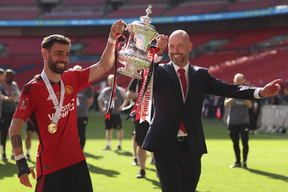 Manchester United's head coach Erik ten Hag and Manchester United's Bruno Fernandes pose with the trophy after winning the English FA Cup final soccer match between Manchester City and Manchester United at Wembley Stadium in London, Saturday, May 25, 2024. (AP Photo/Ian Walton)