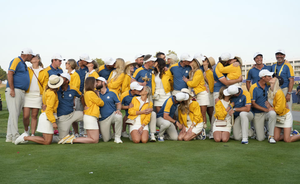 Europe team players and Europe's Team Captain Luke Donald, center, with their wives and partners embrace as they pose for the cameras with the Ryder Cup, after defeating the United States at the Ryder Cup golf tournament at the Marco Simone Golf Club in Guidonia Montecelio, Italy, Sunday, Oct. 1, 2023. (AP Photo/Alessandra Tarantino)