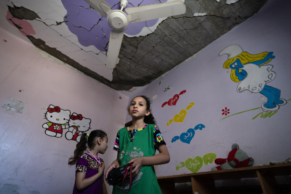 Suroq Al-Masri, 9, and her sister Razan, 4, stand for a portrait in their bedroom that was severely damaged when an airstrike destroyed a neighboring building prior to a cease-fire that halted an 11-day war between Gaza's Hamas rulers and Israel, Wednesday, May 26, 2021, in Beit Hanoun, Gaza Strip. (AP Photo/John Minchillo)