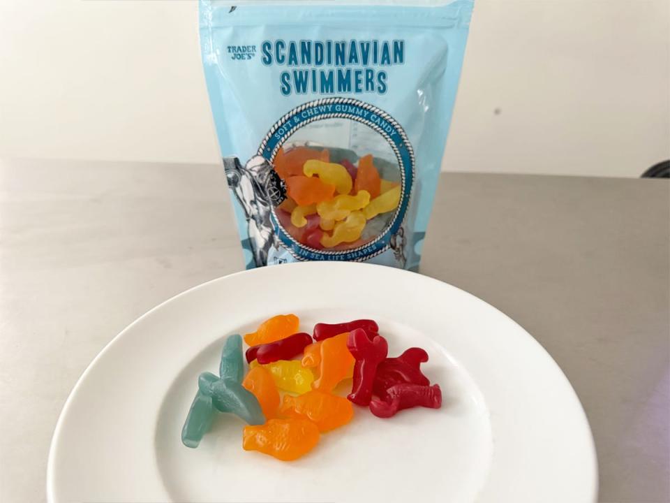 Blue bag of Trader Joe's Scandinavian swimmers with blue, orange, yellow, and red candies on plate in front