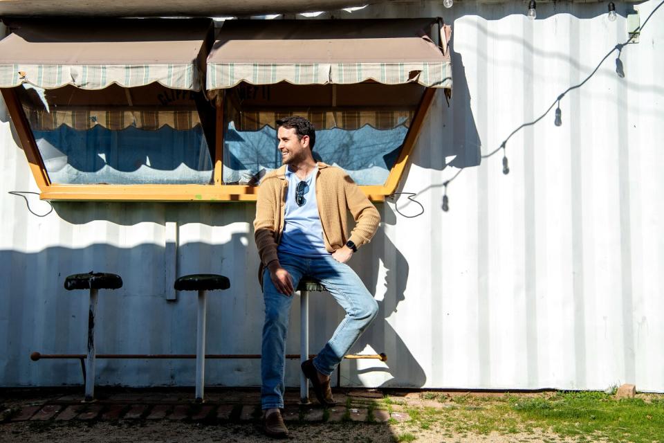 A man seated on an outdoor barstool.