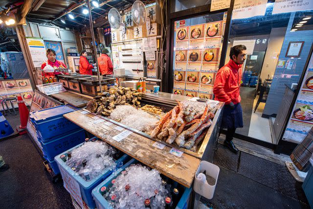 <p>Manorath Naphaphone/Travel + Leisure</p> Vendors at Tsukiji Market, in Tokyo.