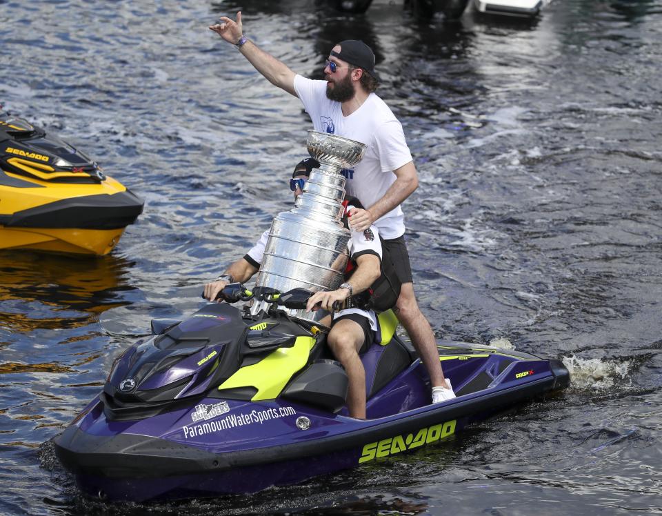 Tampa Bay Lightning left wing Alex Killorn drives a jet ski while holding the Stanley Cup as teammate Nikita Kucherov gestures to the crowd while celebrating the teams NHL hockey Stanley Cup victory with a boat parade Monday, July 12, 2021 in Tampa, Fla. (Dirk Shadd/Tampa Bay Times via AP)