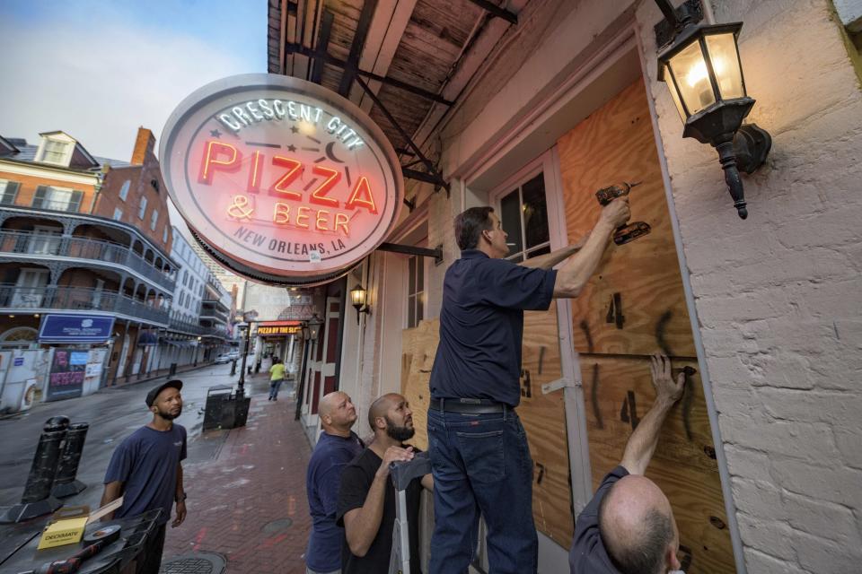 Michael Richard of Creole Cuisine Restaurant Concepts boards up Crescent City Pizza on Bourbon Street in the French Quarter before landfall of Hurricane Ida in New Orleans, Saturday, Aug. 28, 2021. Richard said the group is planning to board up and protect 34 restaurants owned by the company for the storm. (AP Photo/Matthew Hinton)