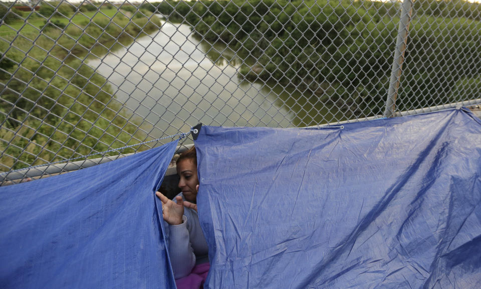 FILE- In this Friday, Nov. 2, 2018, file photo Maidelen Gonzales, an immigrant from Honduras seeking asylum in the United States, waits under a tarp on the Brownsville and Matamoros International Bridge in Matamoros, Mexico. Asylum seekers already camping at border crossings worry that how the Trump administration responds to the caravan of some 4,000 Central American migrants and three much smaller ones hundreds of miles behind it could leave them shut out. (AP Photo/Eric Gay, File)