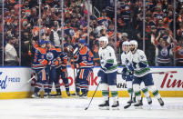 Edmonton Oilers players, left, celebrate a goal against the Vancouver Canucks during the first period of an NHL hockey game in Edmonton, Alberta, Saturday, Oct. 14, 2023. (Jason Franson/The Canadian Press via AP)