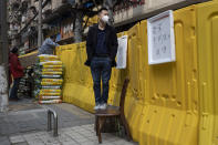 A resident wearing a mask to protect against the spread of the coronavirus looks over barriers used to seal off a neighborhood in Wuhan in central China's Hubei province on Friday, April 3, 2020. Sidewalk vendors wearing face masks and gloves sold pork, tomatoes, carrots and other vegetables to shoppers Friday in the Chinese city where the coronavirus pandemic began as workers prepared for a national memorial this weekend for health workers and others who died in the outbreak. (AP Photo/Ng Han Guan)