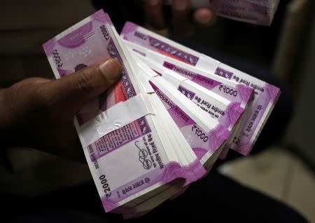 FILE PHOTO: A cashier displays rupee banknotes inside a bank in Jammu, November 15, 2016. REUTERS/Mukesh Gupta/File Photo
