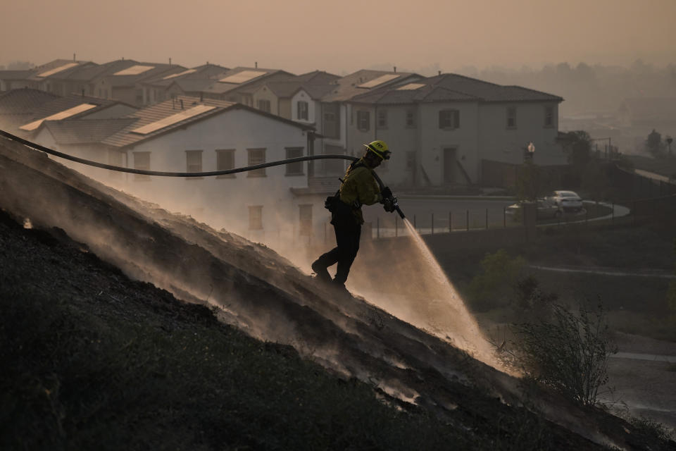 Firefighter Tylor Gilbert puts out hotspots while battling the Silverado Fire, Monday, Oct. 26, 2020, in Irvine, Calif. (AP Photo/Jae C. Hong)