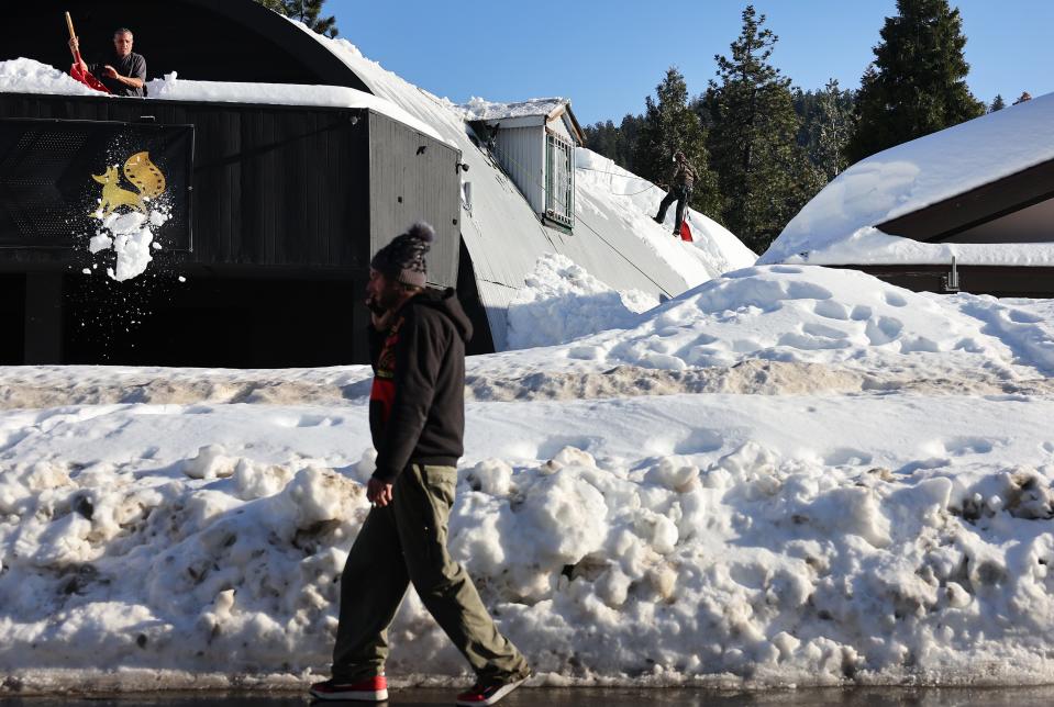 People shovel snow from a roof after a series of winter storms dumped heavy snowfall in the San Bernardino Mountains in Southern California on March 3, 2023 in Crestline, California.