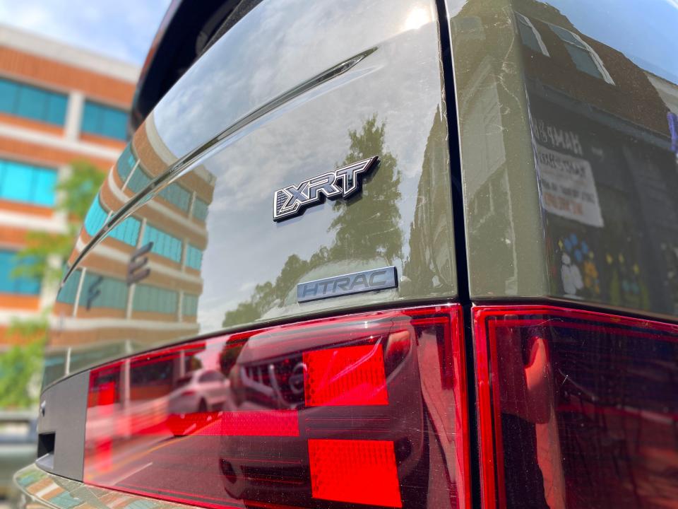 The "XRT" and "HTRAC" emblems on the rear liftgate of a green 2024 Hyundai Santa Fe XRT SUV.