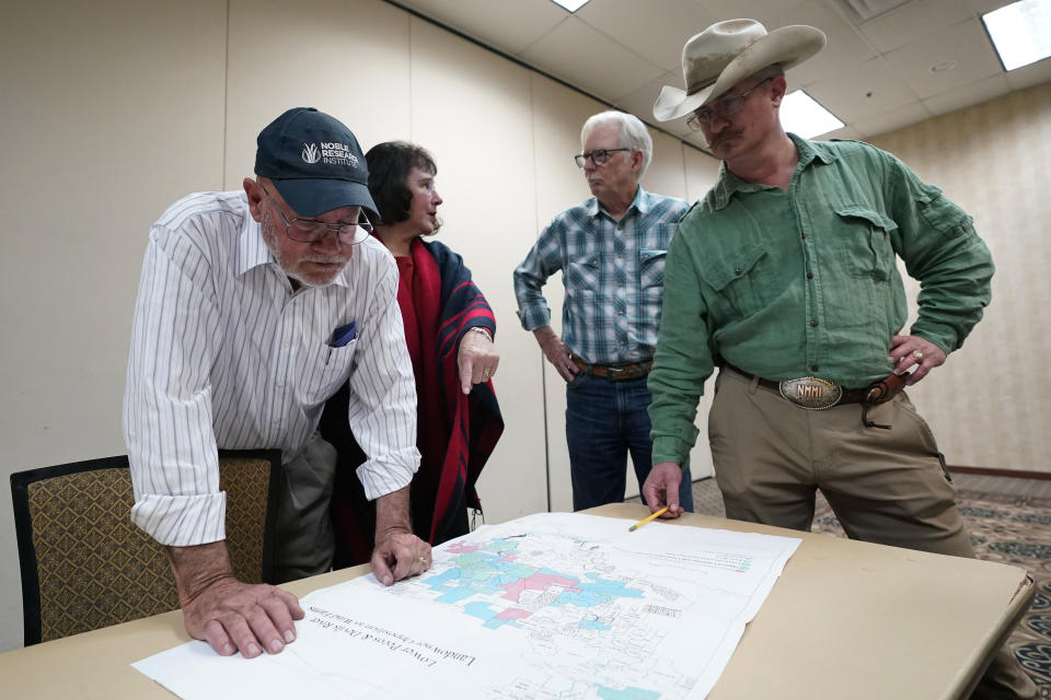 Rancher, from left, Tom Keller, Merily Keller, Randy Nunns and Kerr Wardlaw look over an area map that shows proposed areas for a future wind development, Wednesday, Feb. 15, 2023, in Del Rio, Texas. (AP Photo/Eric Gay)