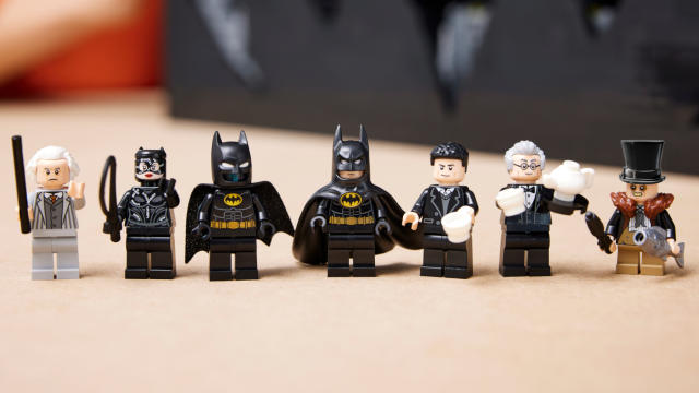 Lego Batman Returns Batcave minifigures, arrayed in a line on a wooden surface