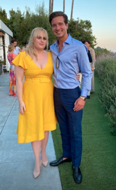 Rebel Wilson in a yellow dress with a male friend