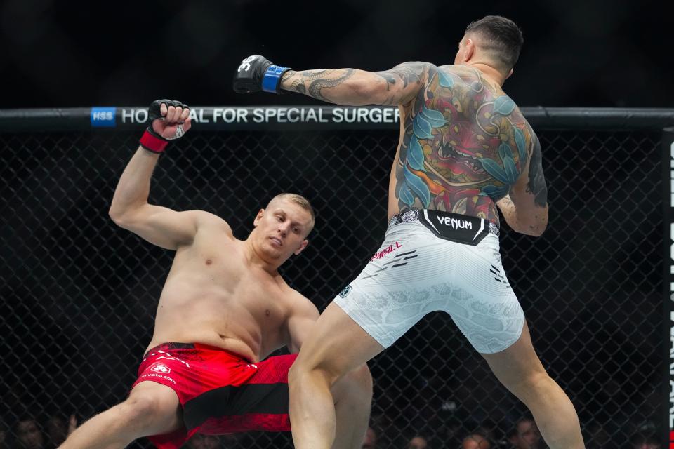 England's Tom Aspinall, right, knocks down Russia's Sergei Pavlovich during the first round of a heavyweight title bout at the UFC 295 mixed martial arts event Saturday, Nov. 11, 2023, in New York. Aspinall stopped Pavlovich in the first round. (AP Photo/Frank Franklin II)