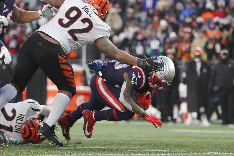 New England Patriots running back Rhamondre Stevenson, right, is brought down by Cincinnati Bengals defensive tackle BJ Hill (92) and cornerback Mike Hilton (21) during the second half of an NFL football game, Saturday, Dec. 24, 2022, in Foxborough, Mass. (AP Photo/Michael Dwyer)