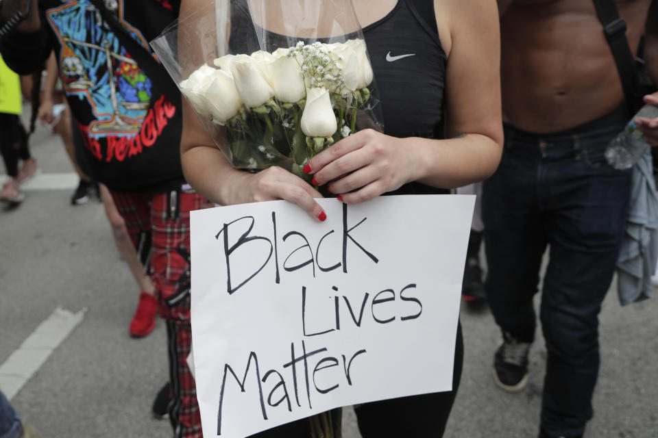 A woman carries a bouquet of flowers as she marches during a protest over the death of George Floyd, Saturday, June 6, 2020, in Miami. Protests continue throughout the country over the death of Floyd, a black man who died after being restrained by Minneapolis police officers on May 25. (AP Photo/Lynne Sladky)