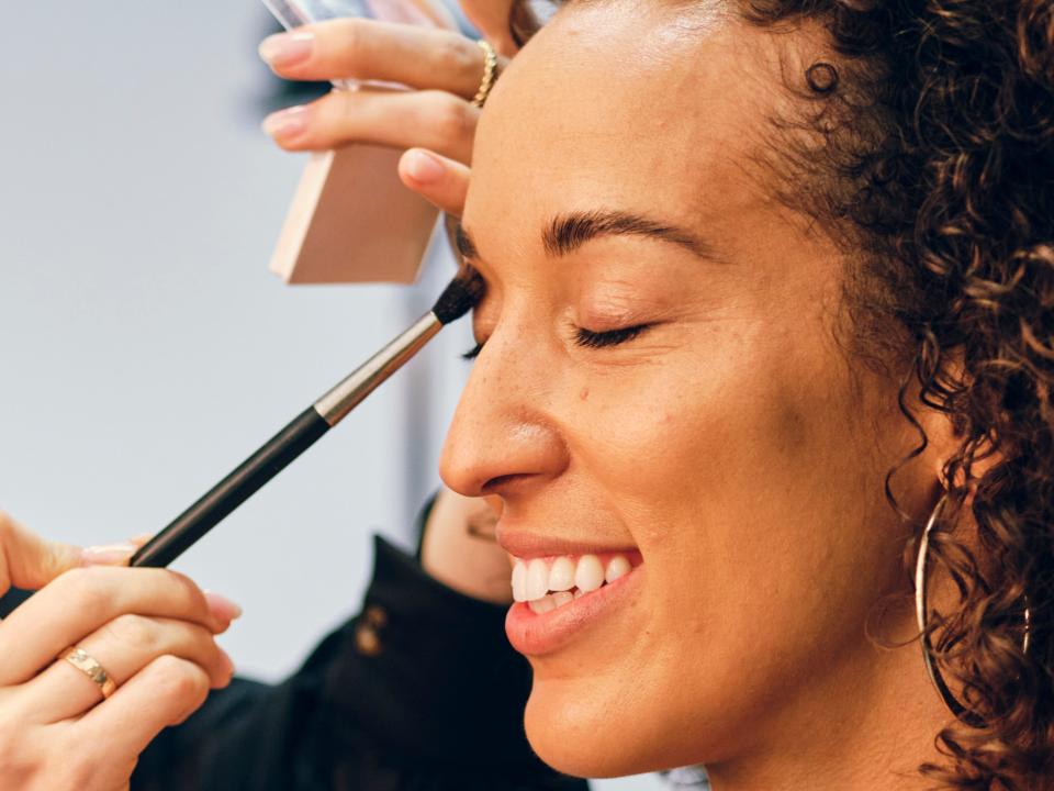 Makeup artist creates look on smiling client