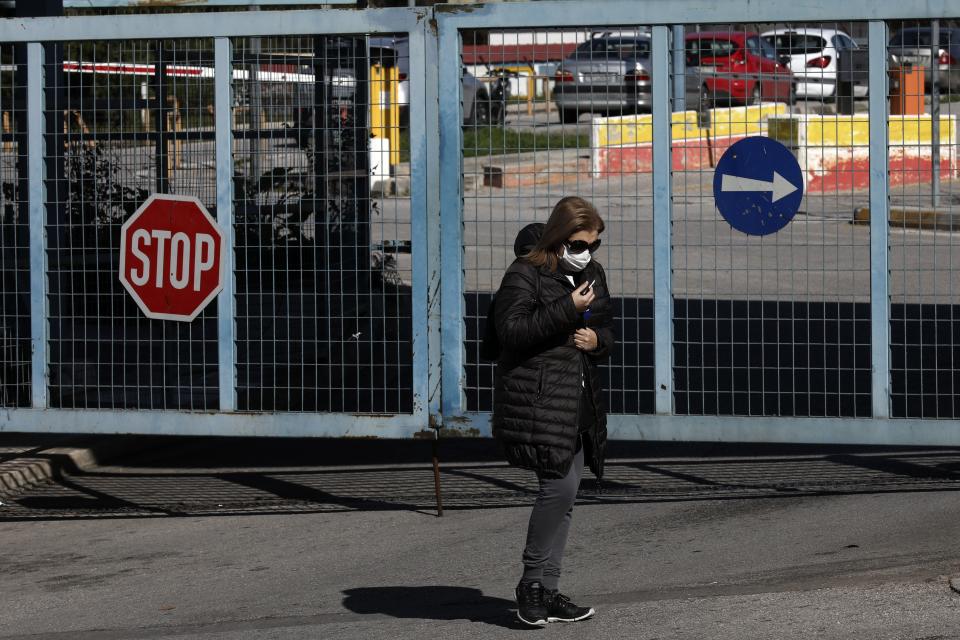 A woman wearing a face mask walks in front of Attiko Hospital in Athens, Saturday, Feb. 29, 2020. Greek Health Ministry said all carnival events in Greece would be suspended as a precautionary measure. (AP Photo/Yorgos Karahalis)