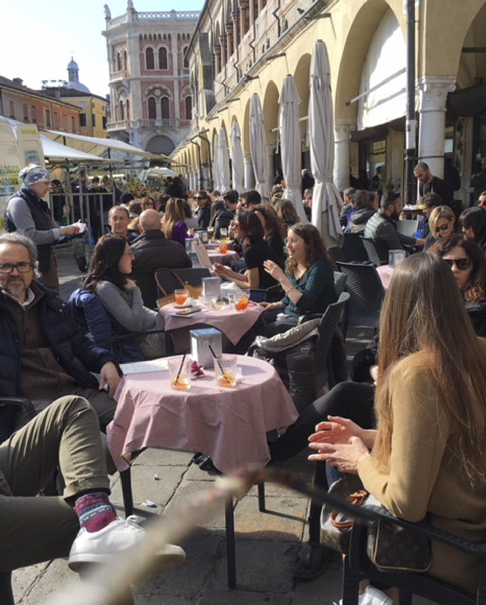 People enjoy their drinks in Piazza delle Erbe square, in Padua, northern Italy, Saturday, March 7, 2020. Chaos and panic exploded in the evening as rumors spread that the Italian government was expanding its lockdown on Northern Italy to help contain the coronavirus, and many people tried to leave before being locked in one of the red areas. (AP Photo/Patricia Thomas)