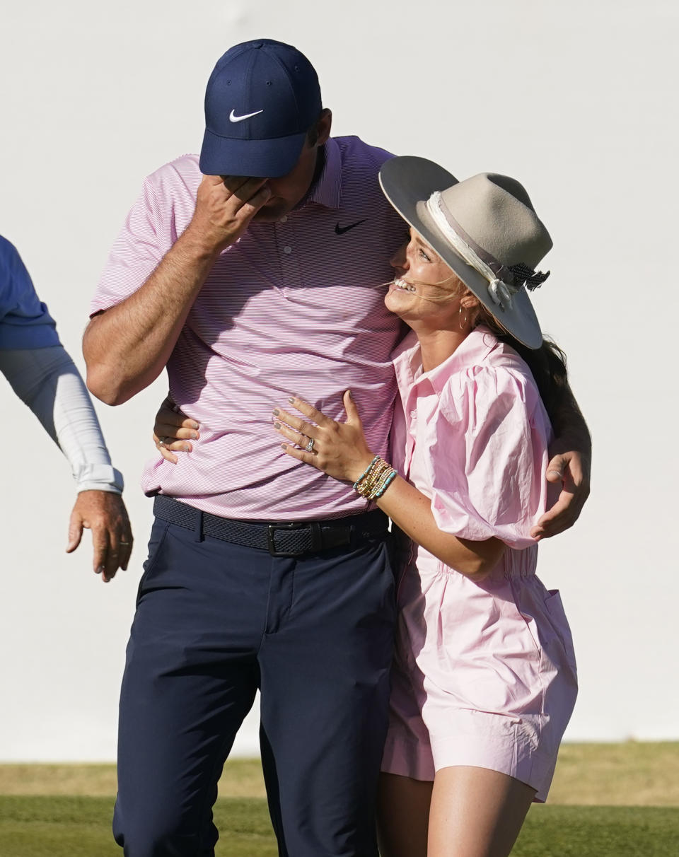 FILE - Scottie Scheffler, left, reacts as he gets a hug from his wife, Meredith, after winning the Dell Technologies Match Play Championship golf tournament March 27, 2022, in Austin, Texas. Scheffler says his wife has come to understand golf a little better in their nine years together. (AP Photo/Tony Gutierrez, File)