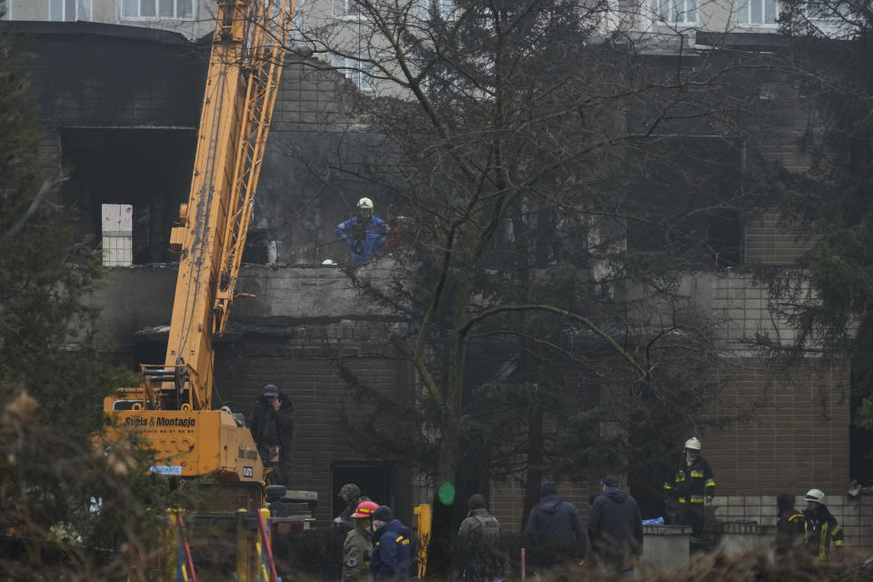 Rescuers work at the scene where a helicopter crashed on civil infrastructure in Brovary, in the outskirts of Kyiv, Ukraine, Wednesday, Jan. 18, 2023. The chief of Ukraine's National Police says a helicopter crash in a Kyiv suburb has killed 16 people, including Ukraine's interior minister and two children. He said nine of those killed were aboard the emergency services helicopter. (AP Photo/Efrem Lukatsky)