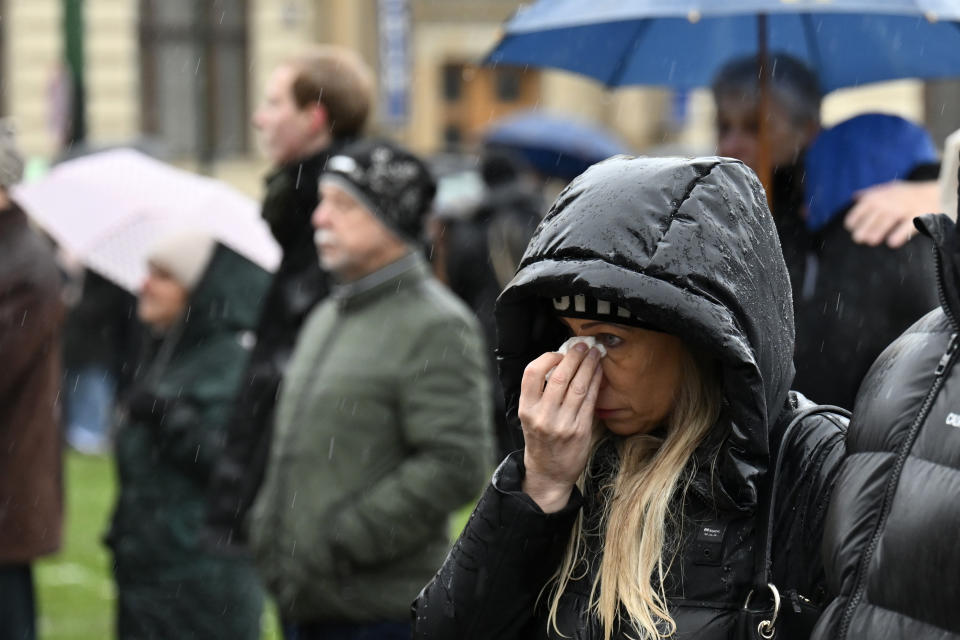 A mourner wipes her eyes in front of the building of Philosophical Faculty of Charles University in downtown Prague, Czech Republic, Saturday, Dec. 23, 2023. A lone gunman opened fire at a university on Thursday, killing more than a dozen people and injuring scores of people. (AP Photo/Denes Erdos)